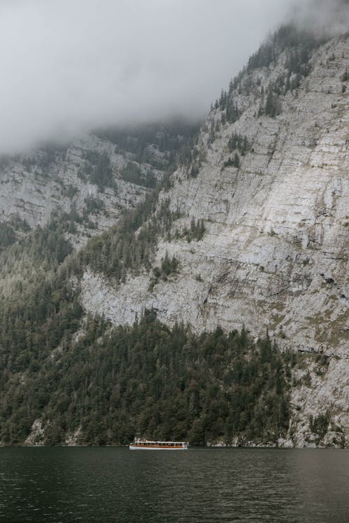 Free Rock Mountains Near Body of Water and Covered by Clouds Stock Photo