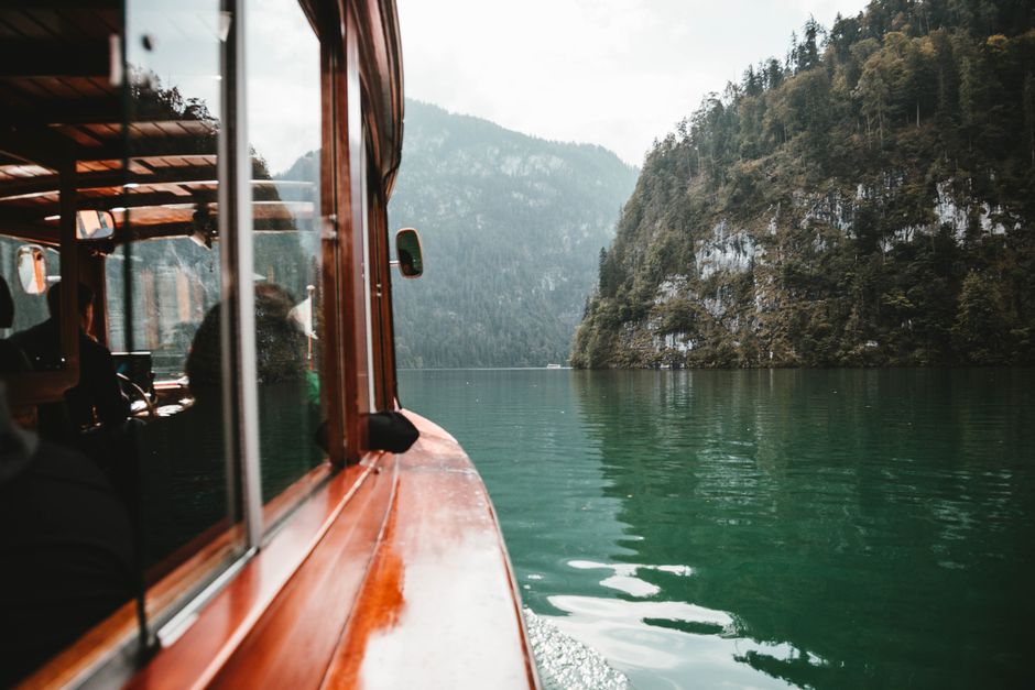 View from a wooden boat on the picturesque Königssee, surrounded by lush cliffs in Schoenau, Germany.