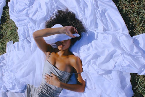 Woman Lying Down and Covering Face with White Fabric