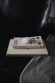 A cozy indoor scene featuring design books stacked with wireless earphones.