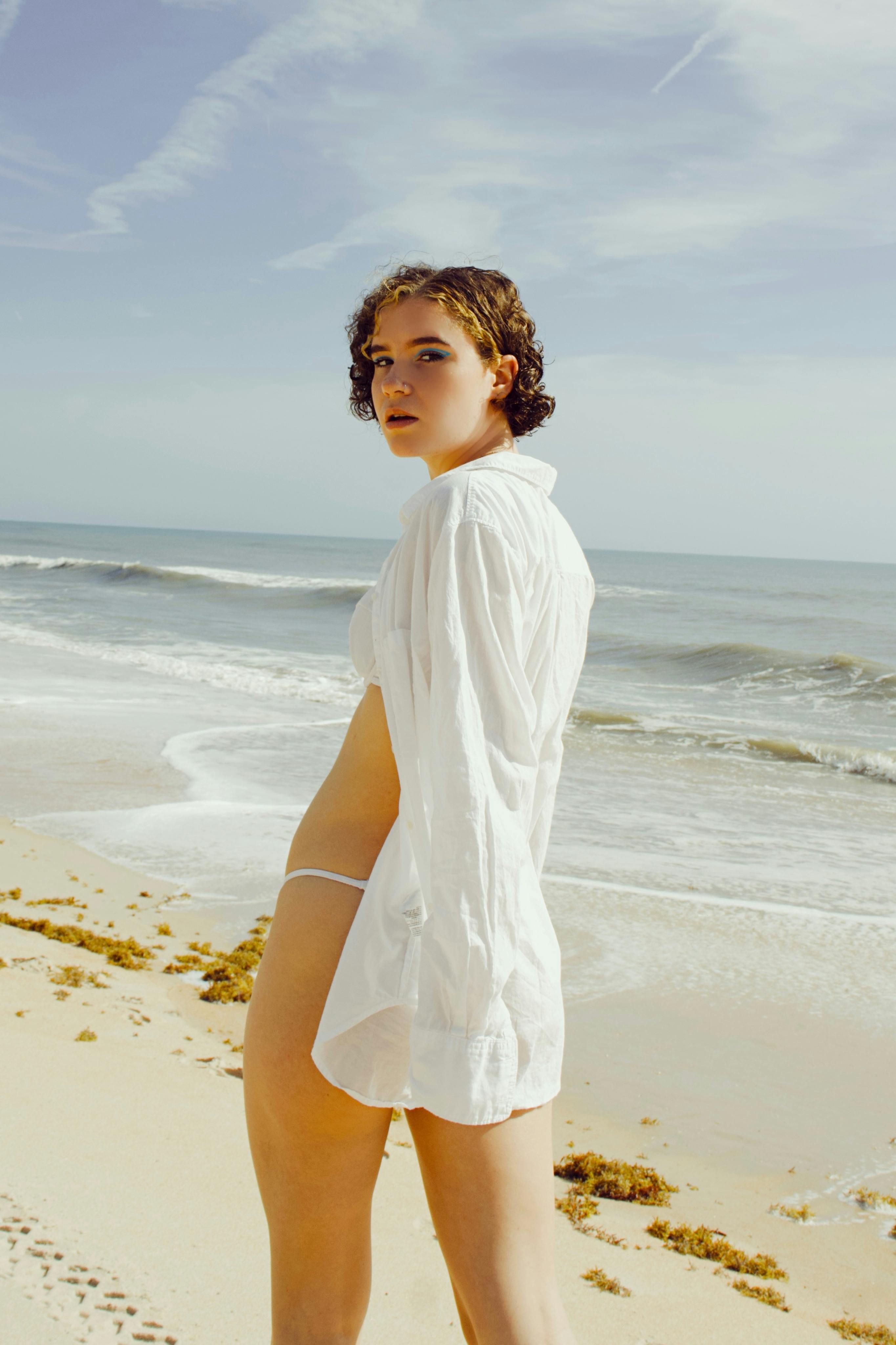 一个穿着白衬衫的女人自信地在阳光明媚的佛罗里达海滩上摆姿势