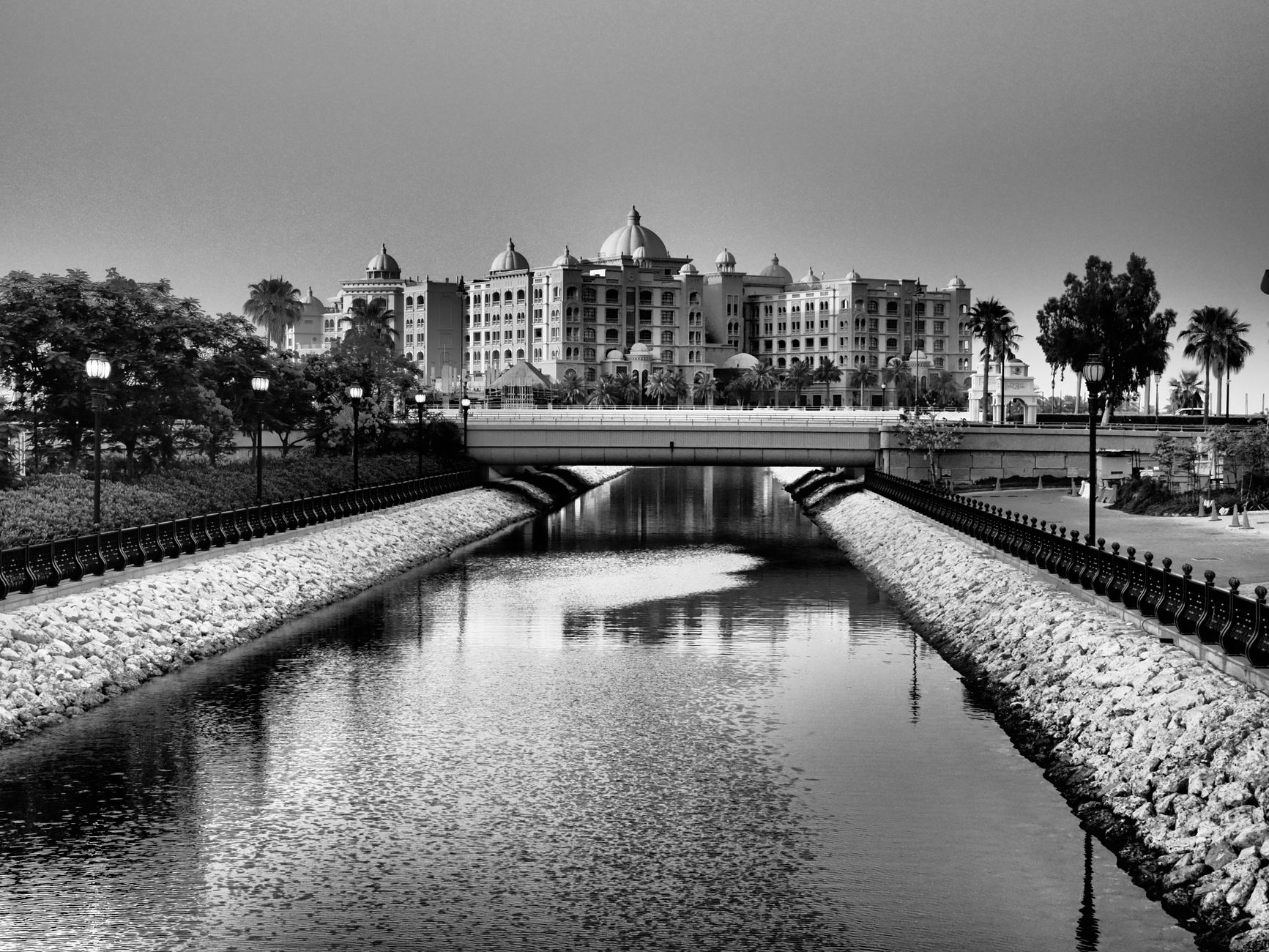 Black and white view of Marsa Malaz Kempinski reflecting in a tranquil canal in Doha, Qatar.