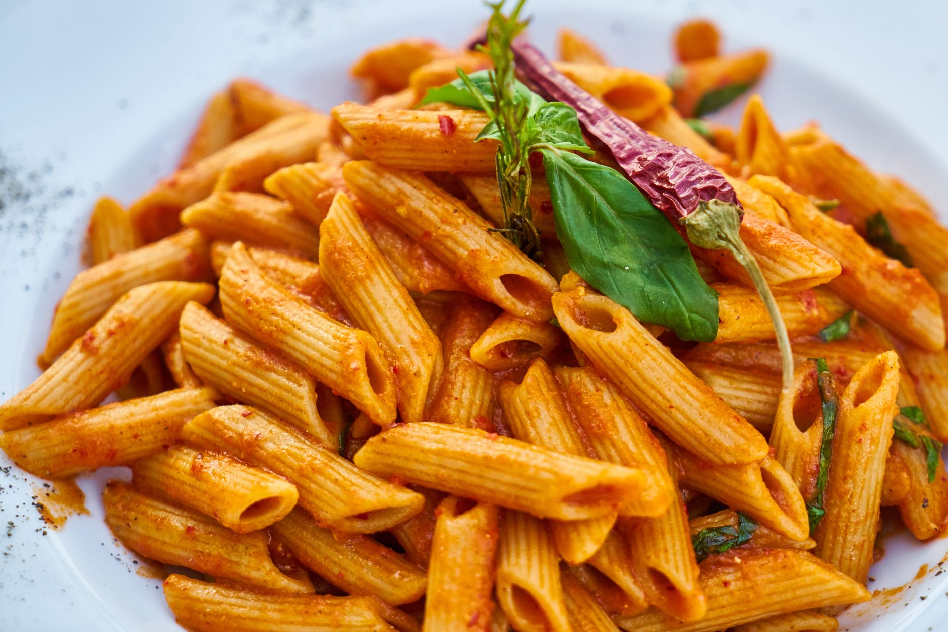Bowl of penne all'arrabbiata pasta with spicy tomato sauce, red pepper flakes, and fresh basil