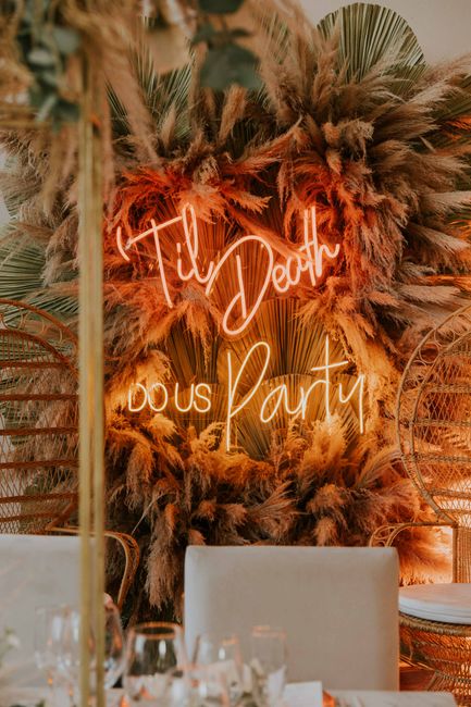 Boho chic wedding backdrop with neon sign and dried flowers.