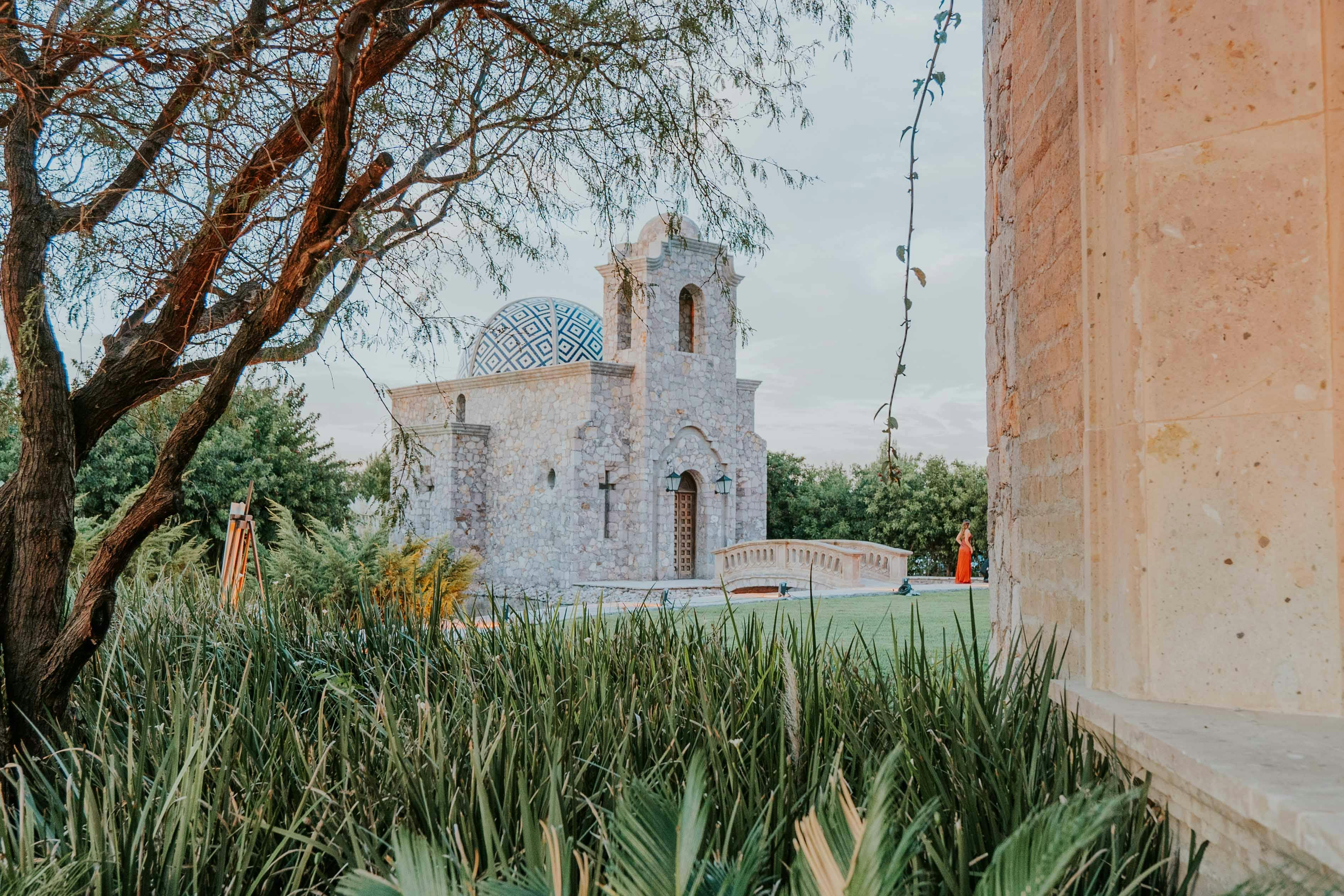 Picturesque stone chapel nestled in lush greenery with unique architecture and serene atmosphere.