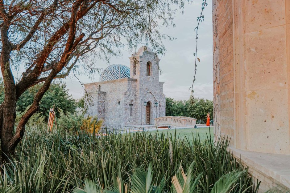 Picturesque stone chapel nestled in lush greenery with unique architecture and serene atmosphere.