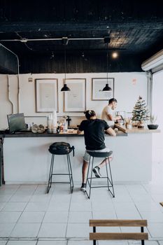 Modern café with customer at counter, enjoying a drink while barista prepares coffee. Bright, welcoming atmosphere.