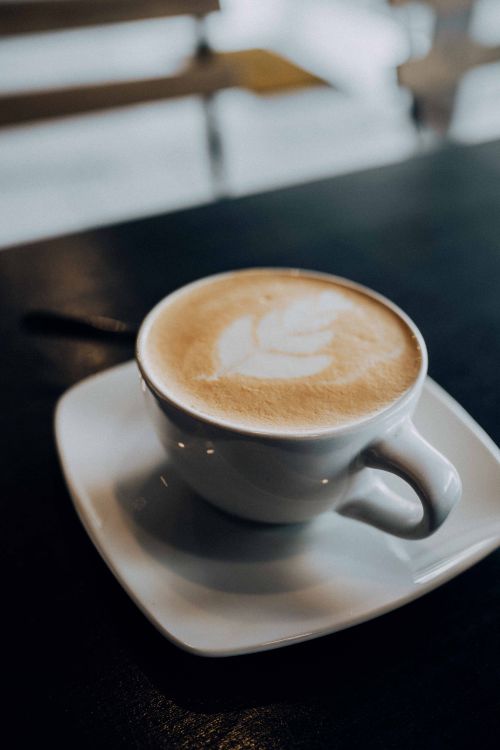 Free Close-up of a cappuccino with intricate latte art in a cozy cafe. Perfect for coffee lovers. Stock Photo