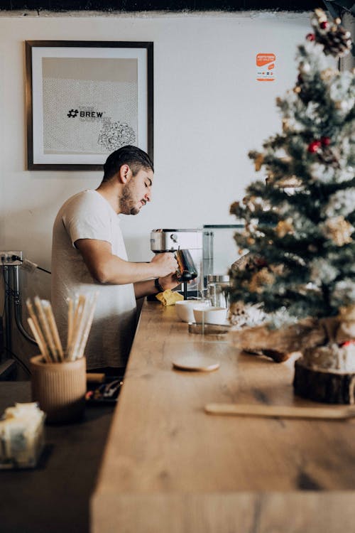 Man Menuangkan Minuman Dari Mesin Dekat Pohon Natal Di Meja