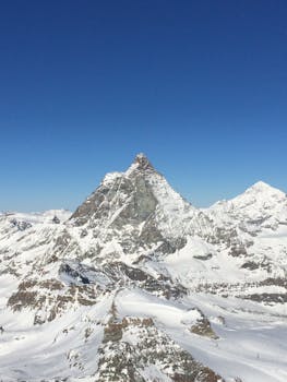 A stunning aerial view of the snow-covered Matterhorn mountain in Zermatt, Switzerland, under a clear blue sky.
