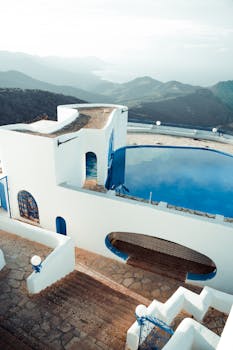 Elevated view of a luxurious white building with pool overlooking mountains in Annaba, Algeria.