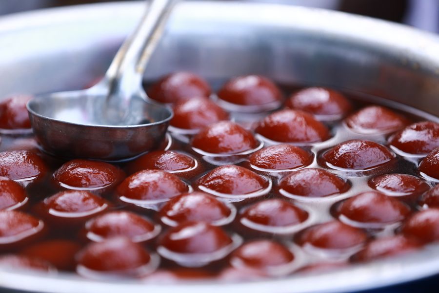 Close-up view of Gulab Jamun in a stainless steel pot, popular Indian dessert street food.