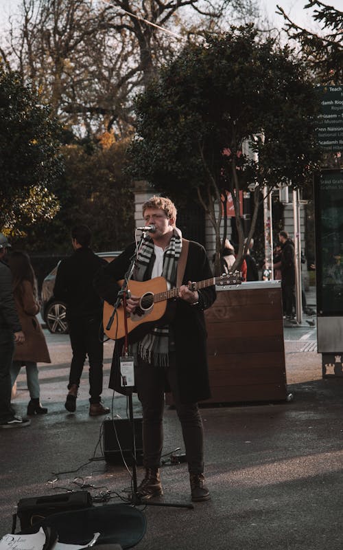 Man Singing and Playing the Guitar on a Street
