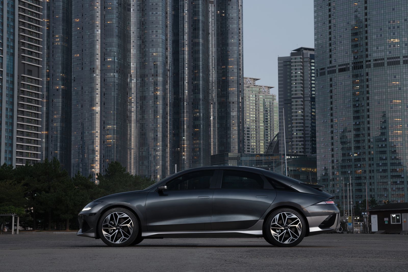 Dark grey fastback sedan parked in a city at dusk