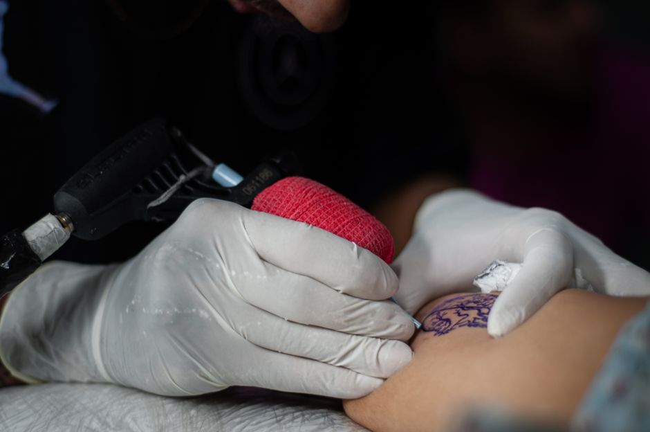 Tattoo apprentice practicing controlled needle depth on thick skin during hands-on mentorship Tattoo apprentice practicing controlled needle depth on thick skin during hands-on mentorship