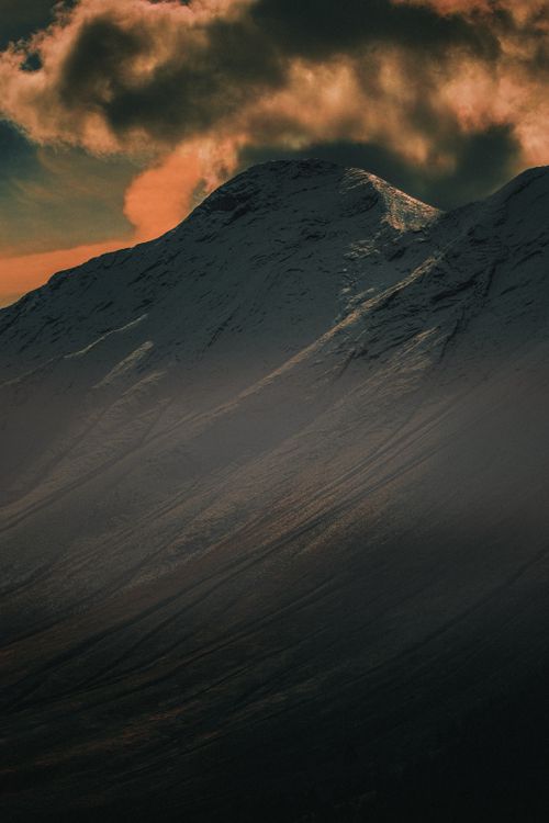 Free Breathtaking view of a snow-covered mountain with a dramatic sunset sky, perfect for nature enthusiasts. Stock Photo
