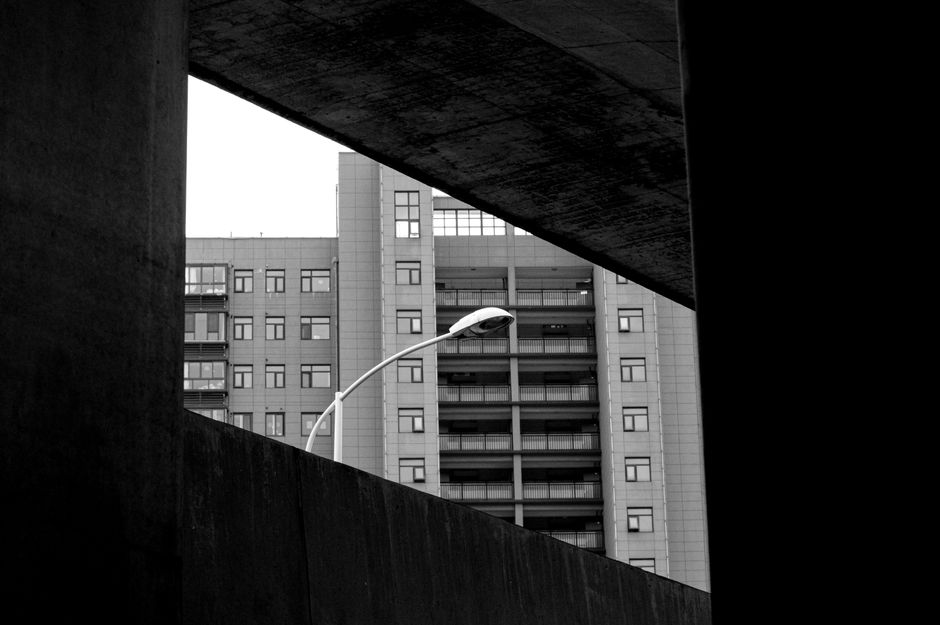 Black and white view of a high-rise building through a concrete frame, showcasing modern urban architecture.