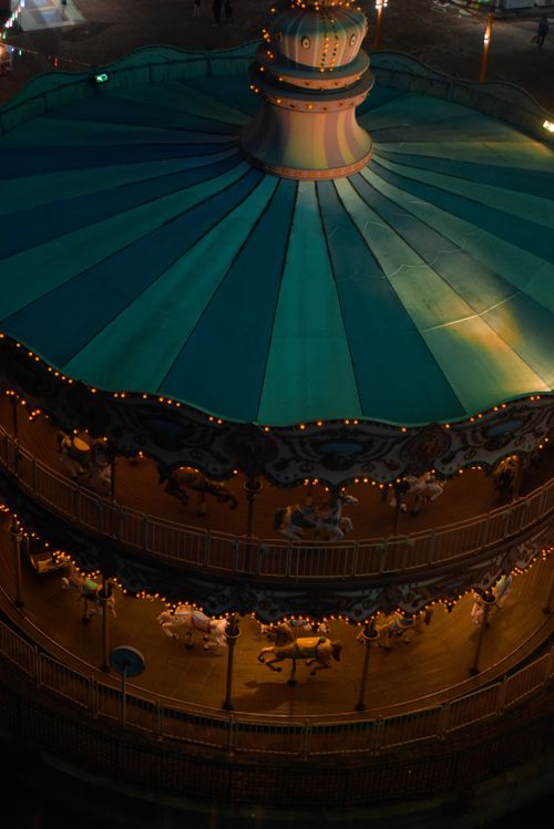 Free A beautifully illuminated carousel with teal and gold colors seen from above at night. Stock Photo