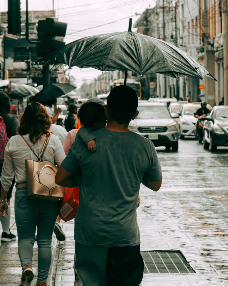 Man Walking With A Baby Under An Umbrella 