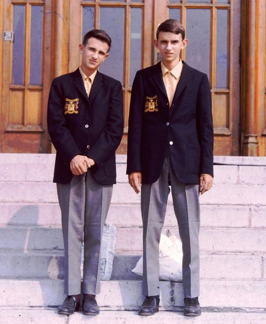 Two teenagers in school uniforms pose on steps outside a building, showcasing formal attire. Two teenagers in school uniforms pose on steps outside a building, showcasing formal attire.