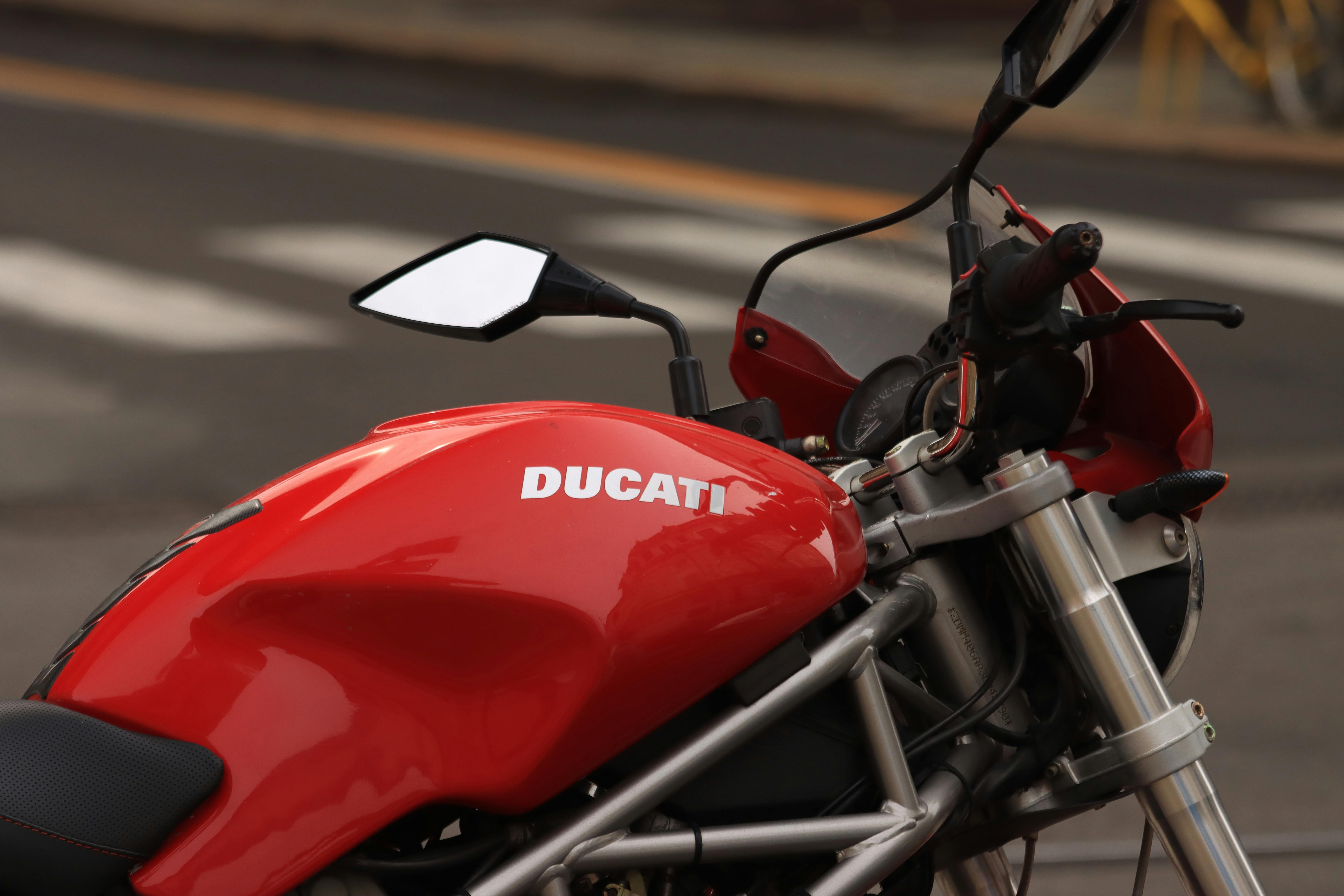 A detailed view of a red Ducati motorcycle parked on an urban street.