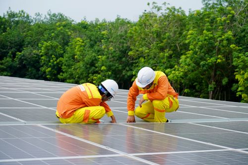 Free Workers installing photovoltaic solar panels on a sunny day, promoting renewable energy. Stock Photo