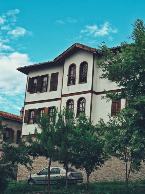 Free Charming traditional house amidst lush greenery under a vibrant blue sky. Stock Photo