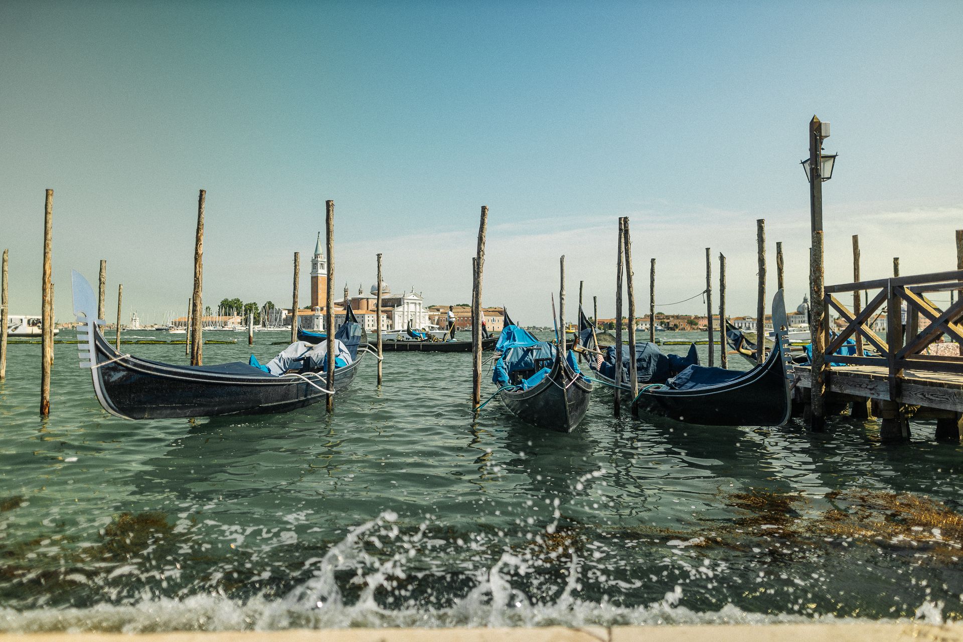 A picturesque view of gondolas docked at a Venetian harbor with iconic architecture.