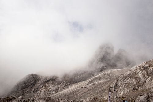 Free Clouds embrace the rocky peaks of Yulong Mountain, creating a mystical atmosphere. Stock Photo