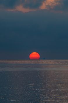 Serene sunset view over the sea in Bagnara Calabra, Italy, featuring a vivid orange sun.