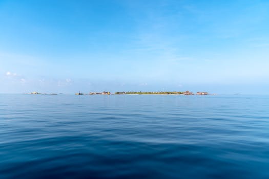 Serene sea view with distant island and calm blue sky, perfect for relaxation themes.
