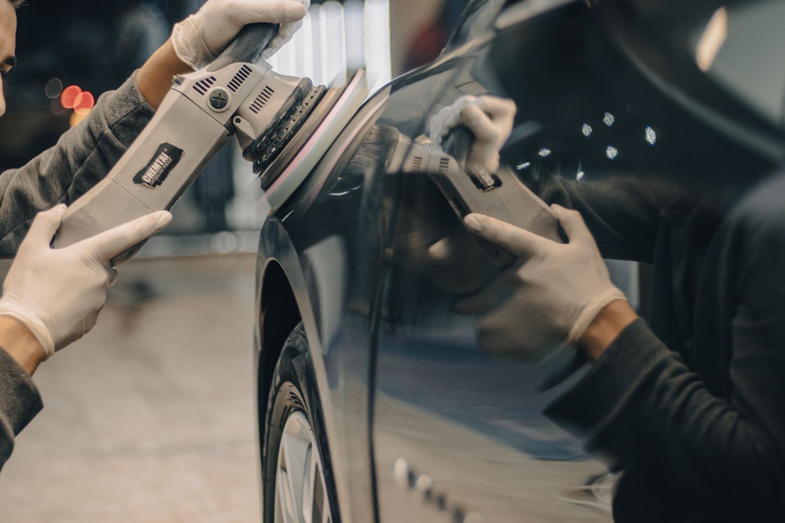 Detailer machine polishing the dark paint of a luxury vehicle during a one-step gloss enhancement