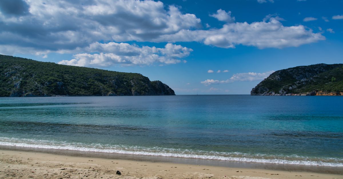 A shallow Greek beach with clear turquoise water and no waves