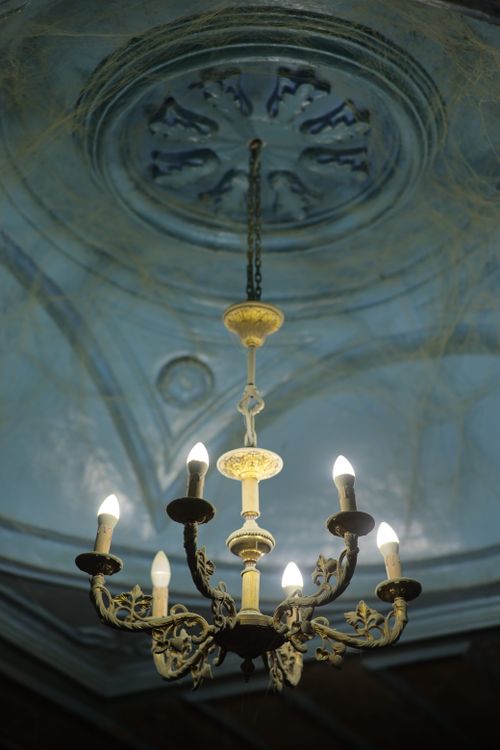 Free A luxurious gold chandelier hangs against an ornate carved ceiling, exuding vintage elegance. Stock Photo