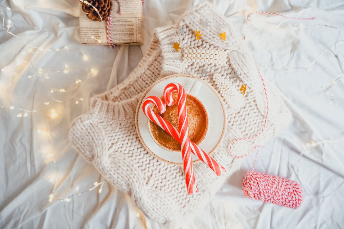 Warm winter scene featuring hot cocoa, candy canes, and a knitted sweater for a perfect seasonal vibe.