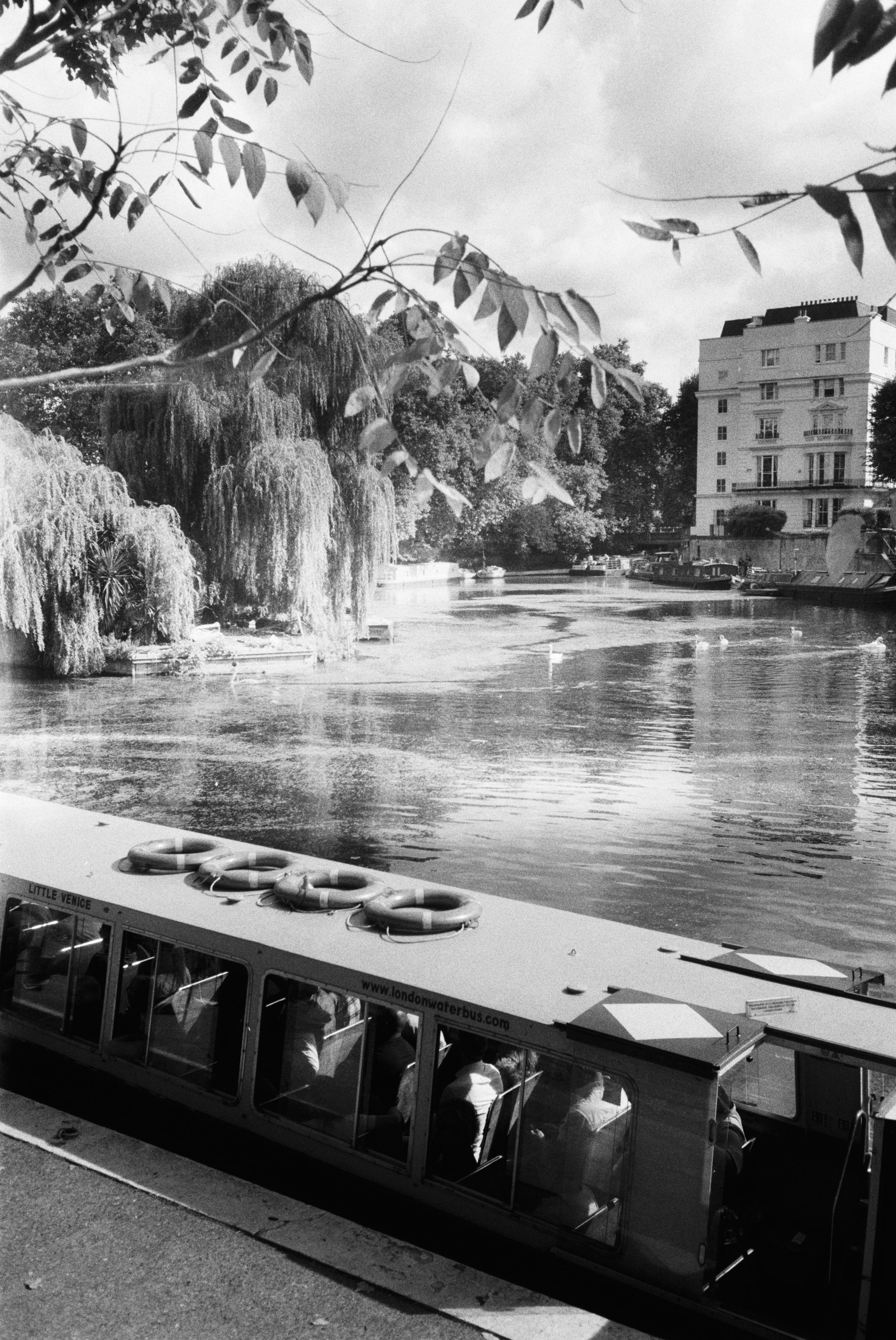 Elegant black and white image of a canal in London, featuring a boat and buildings.
