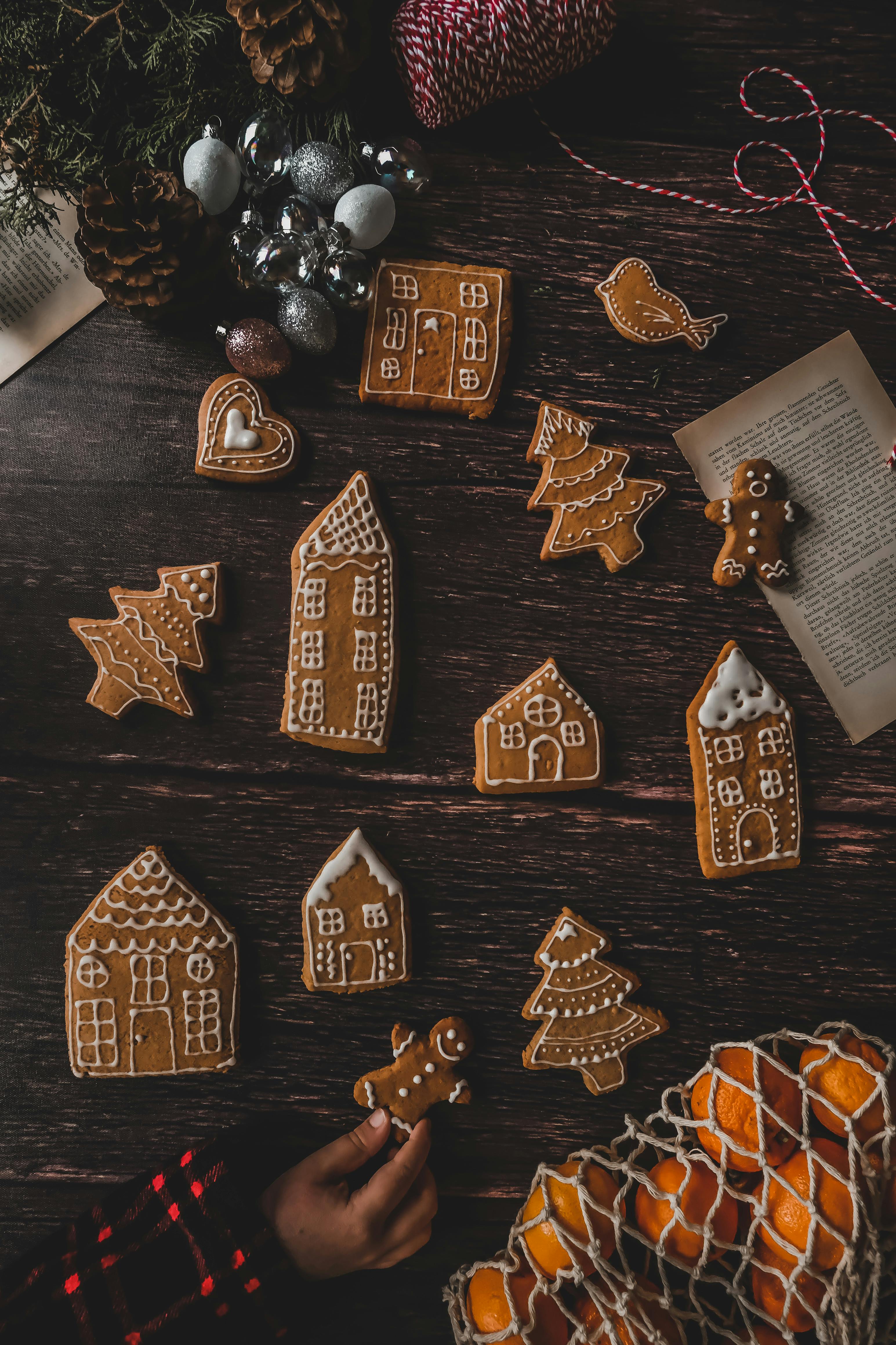 A warm Christmas-themed flatlay with gingerbread cookies and oranges on a wooden surface.