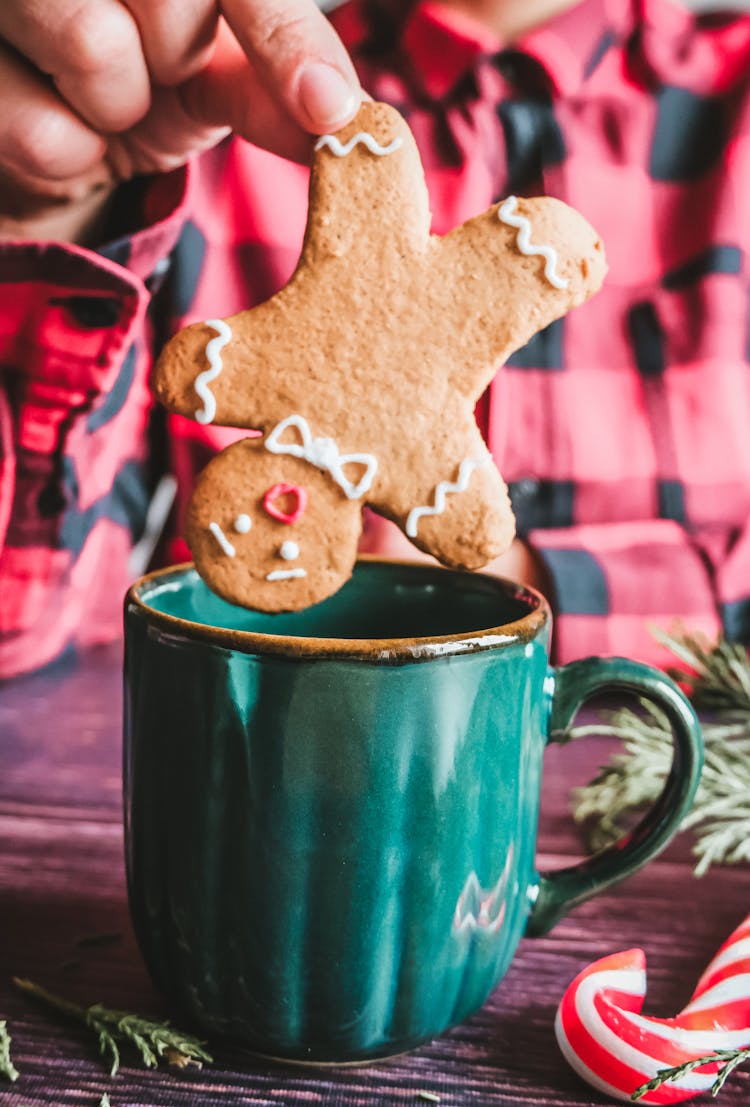 Close-up Of Person Eating Gingerbread Cookie With Hot Drink