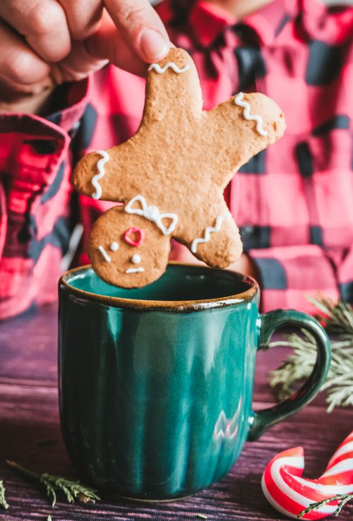 Free A gingerbread cookie being dipped into a cozy holiday drink in a festive setting. Stock Photo