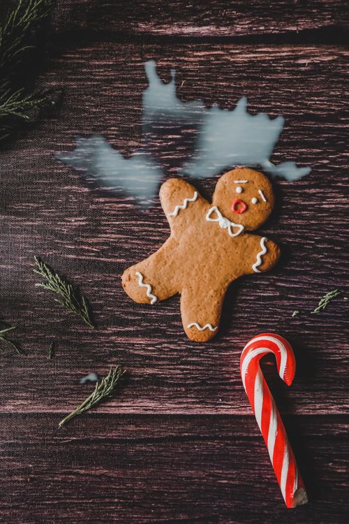 Free Festive image of a gingerbread man and candy cane on a rustic wooden table, perfect for Christmas themes. Stock Photo