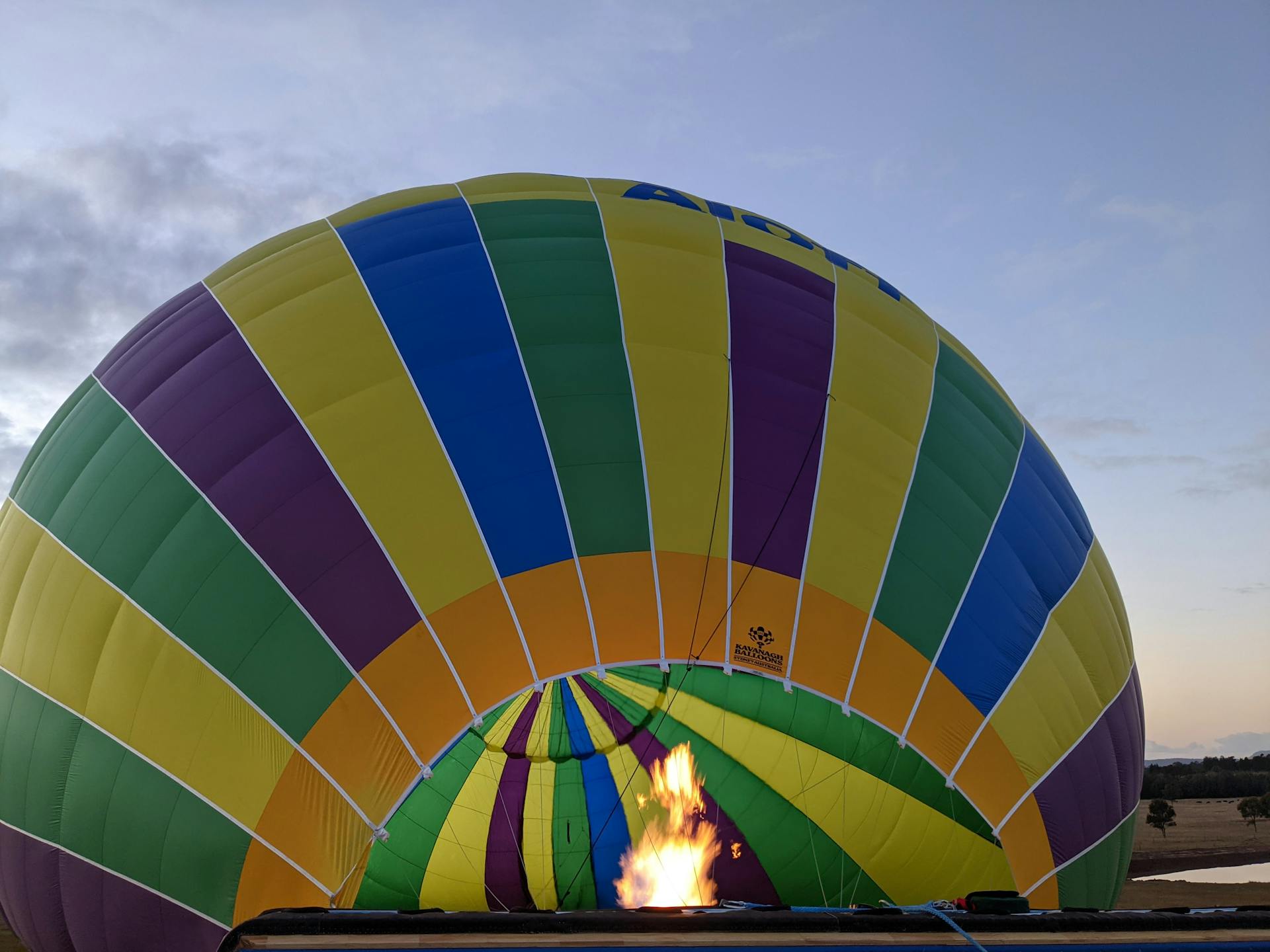 Colorful hot air balloon inflating with fire during a clear day outdoors.