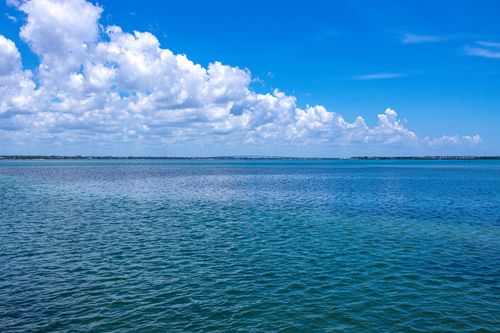 Free Vast ocean expanse meets a picturesque sky filled with fluffy clouds on a clear day. Stock Photo