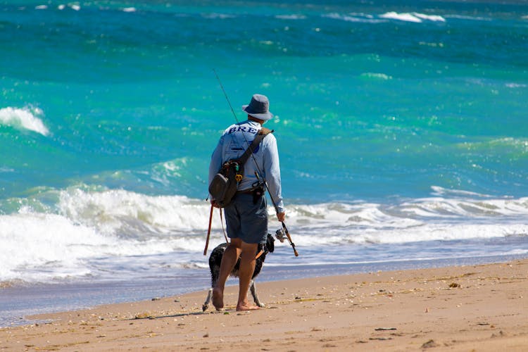 Man With A Fishing Road Walking With A Dog