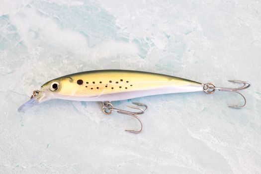 Close-up of a detailed fish-shaped fishing lure on a textured white background.