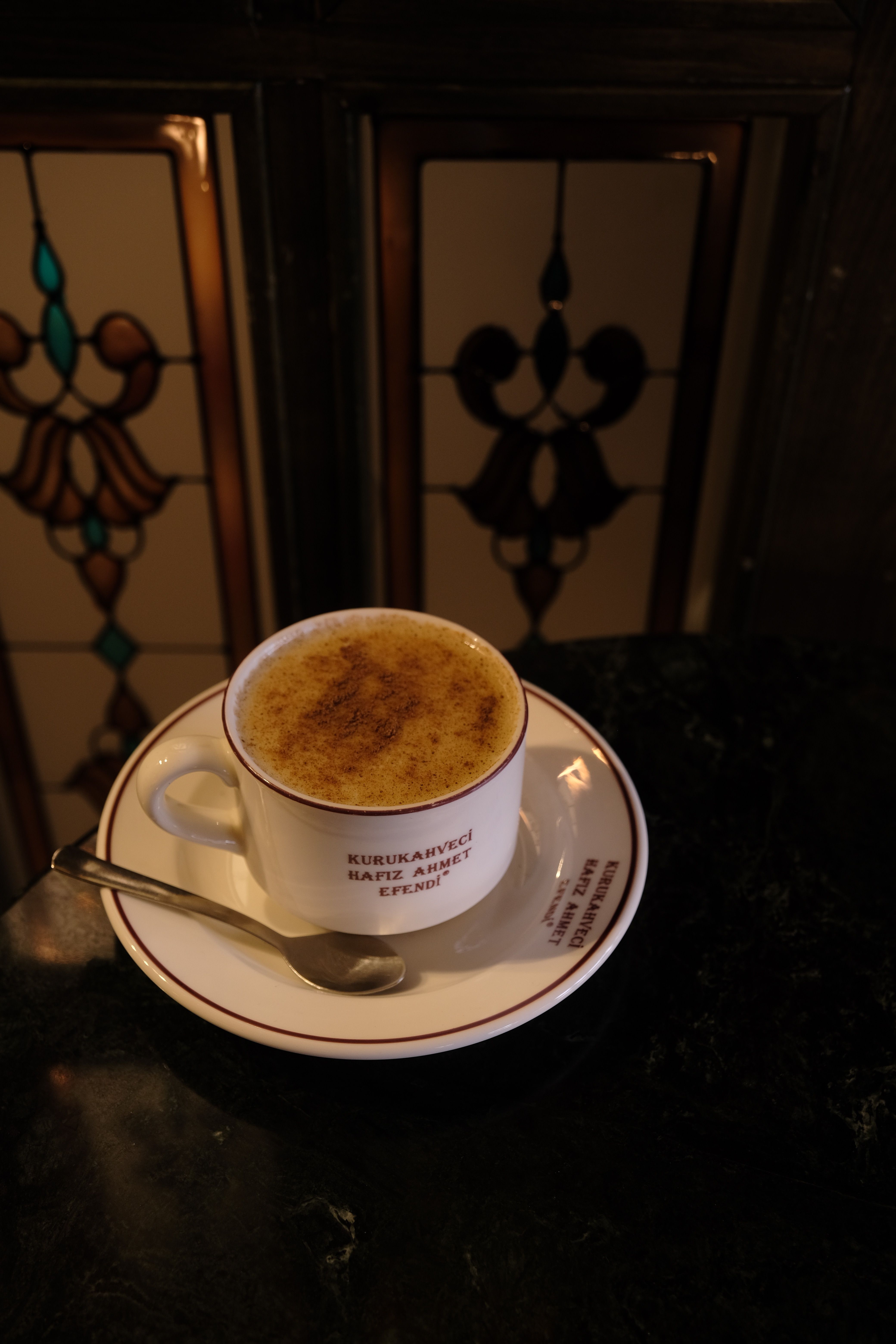 A white coffee cup with saucer on black marble surface, elegant cafe ambiance.