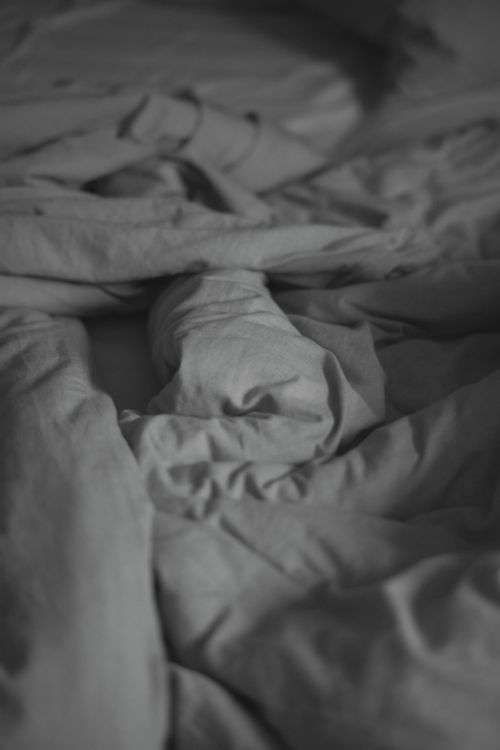 Free Artistic close-up of creased, messy bed linens in a soft, muted tone, perfect for abstract and minimalist themes. Stock Photo