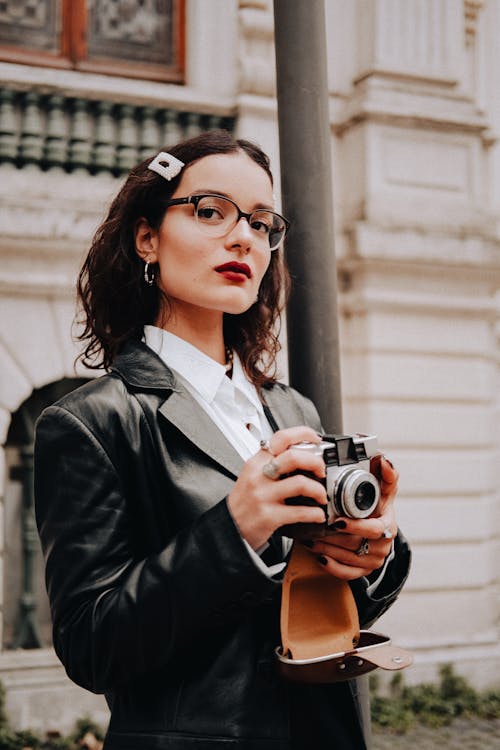 Woman in Leather Coat Holding a Vintage Camera