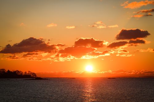 Free Serene sunrise over Stamford's waterfront with vibrant sky and calm sea. Stock Photo