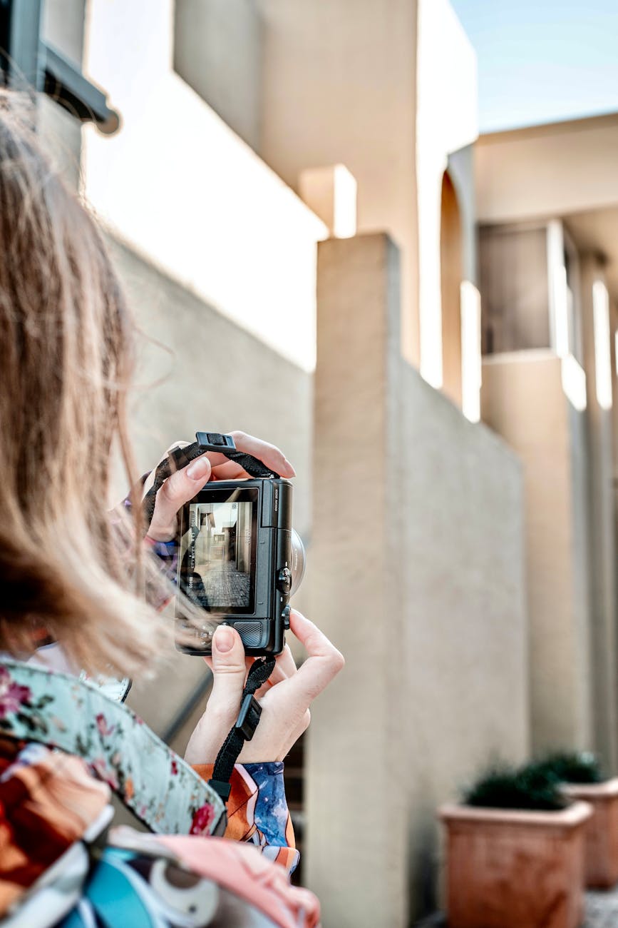 Woman photographing modern architecture with a camera outdoors.