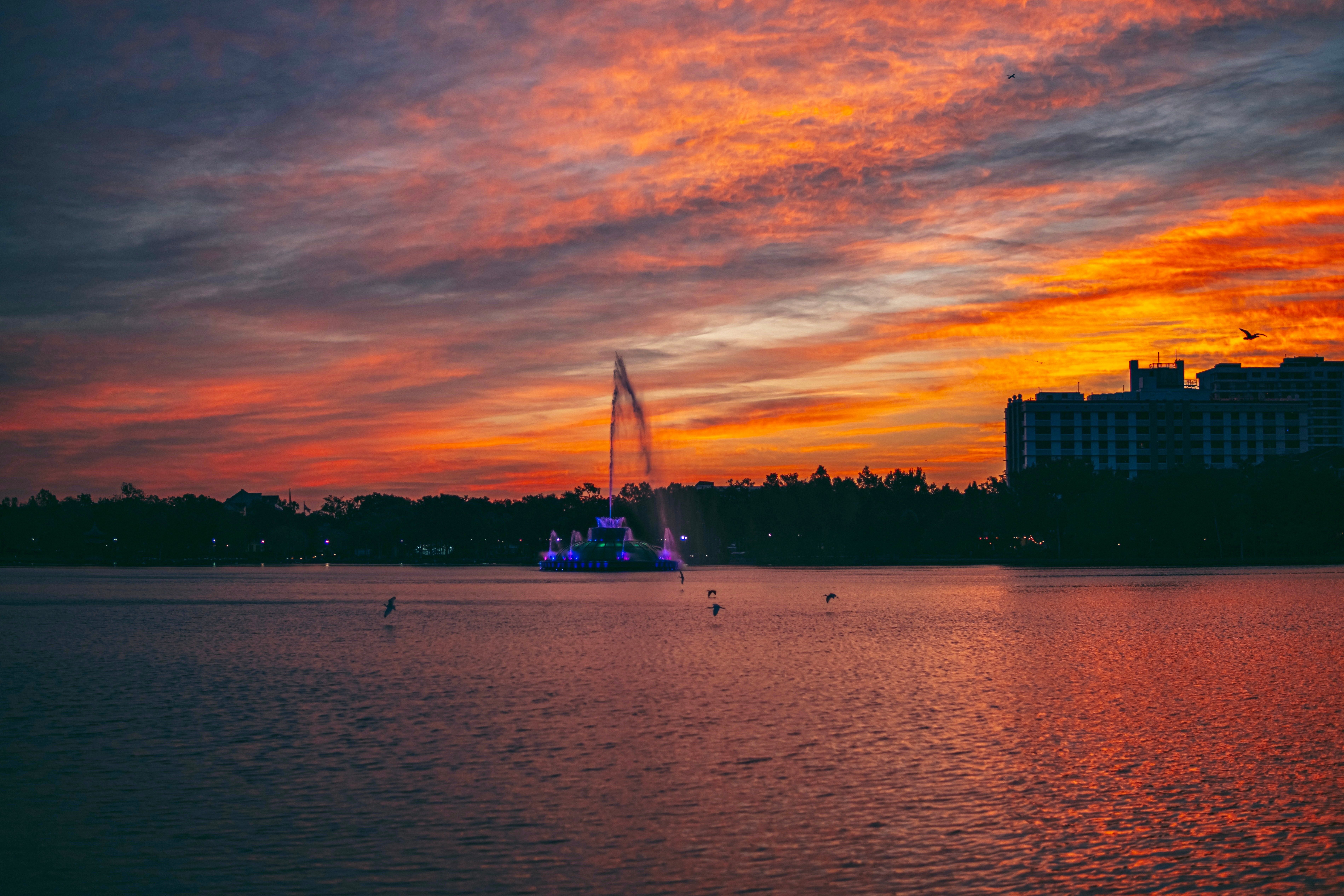 Dazzling sunset view of Lake Eola with vibrant sky reflecting on water in Orlando.